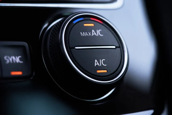 Close-up of a car's black air conditioning control knob labeled MAX A/C and A/C with orange indicator lights illuminated.