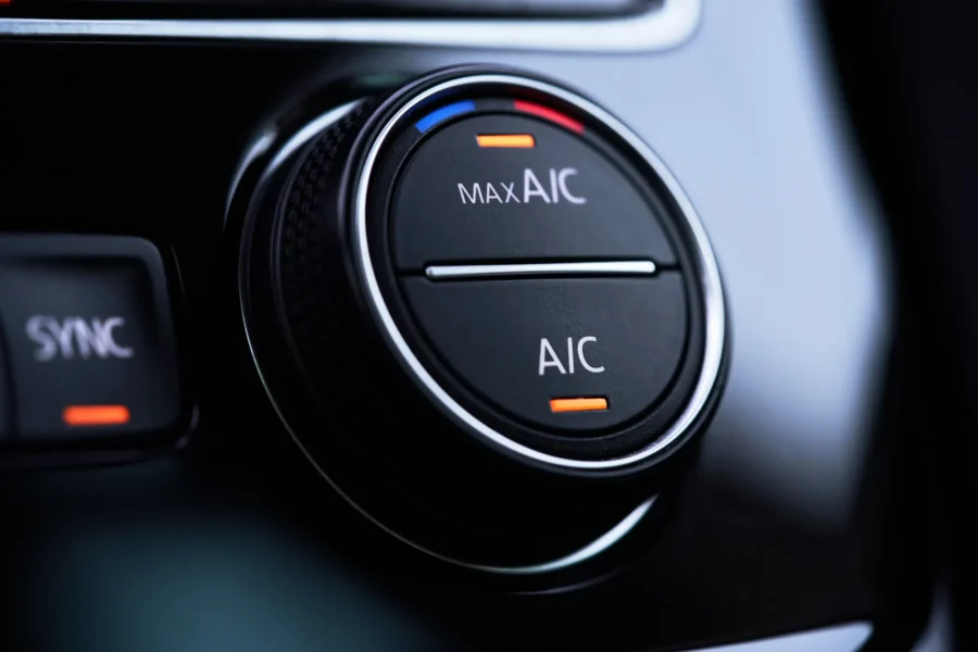Close-up of a car's black air conditioning control knob labeled MAX A/C and A/C with orange indicator lights illuminated.